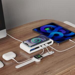 Multiple devices charging on a wooden desk.