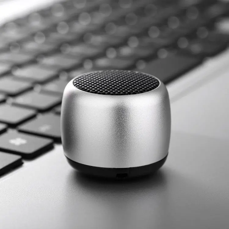 Mini silver speaker on laptop keyboard.